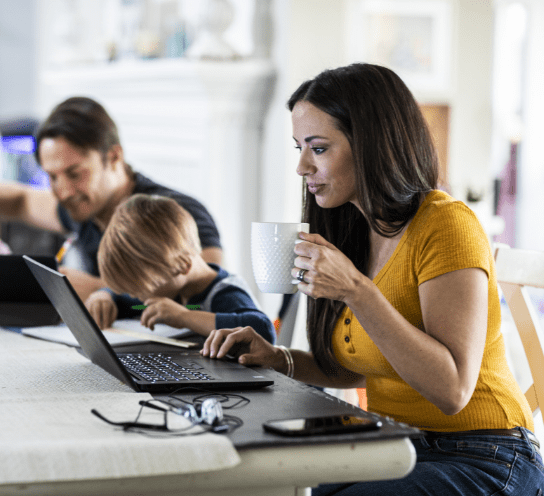 Woman drinking coffee and interacting with laptop