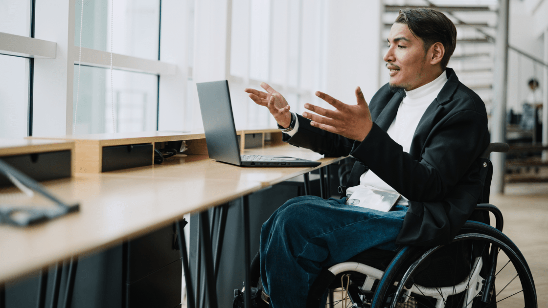 A man in a wheelchair talking to someone on a computer
