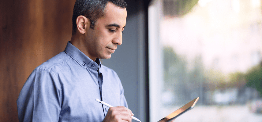 A man looks thoughtfully at a tablet while holding a digital pen.