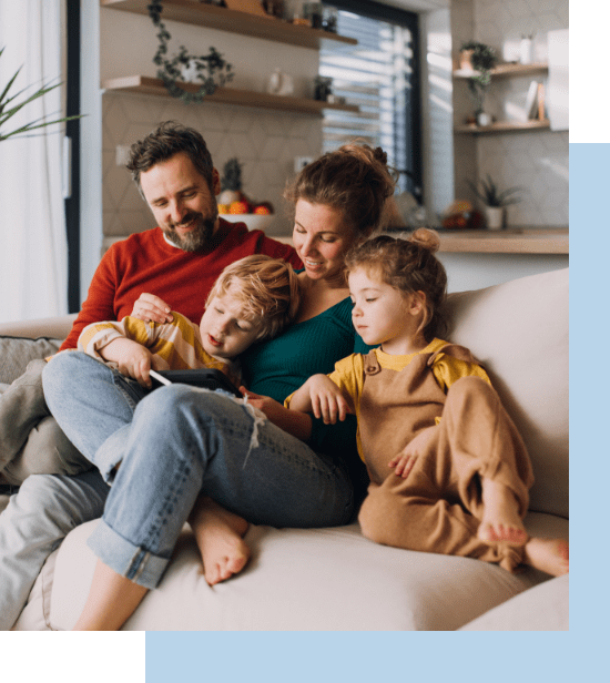 Happy family sitting closely on the couch interacting over a tablet device.